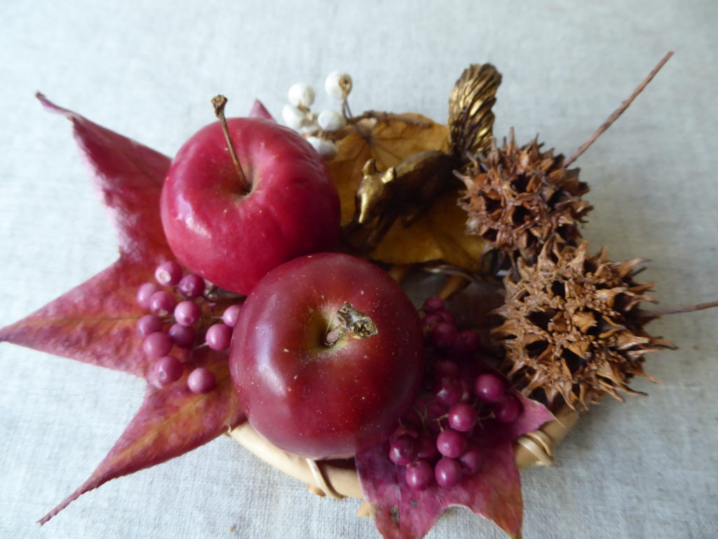 小さなチーズトレイに姫リンゴと落ち葉その他ドライ素材を飾り付けた秋の実りのアソートレンジの見本写真