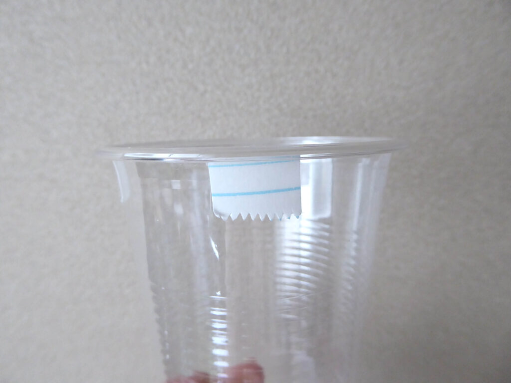 プラスチックカップの外側フチの下に両面テープを貼り付けた写真
