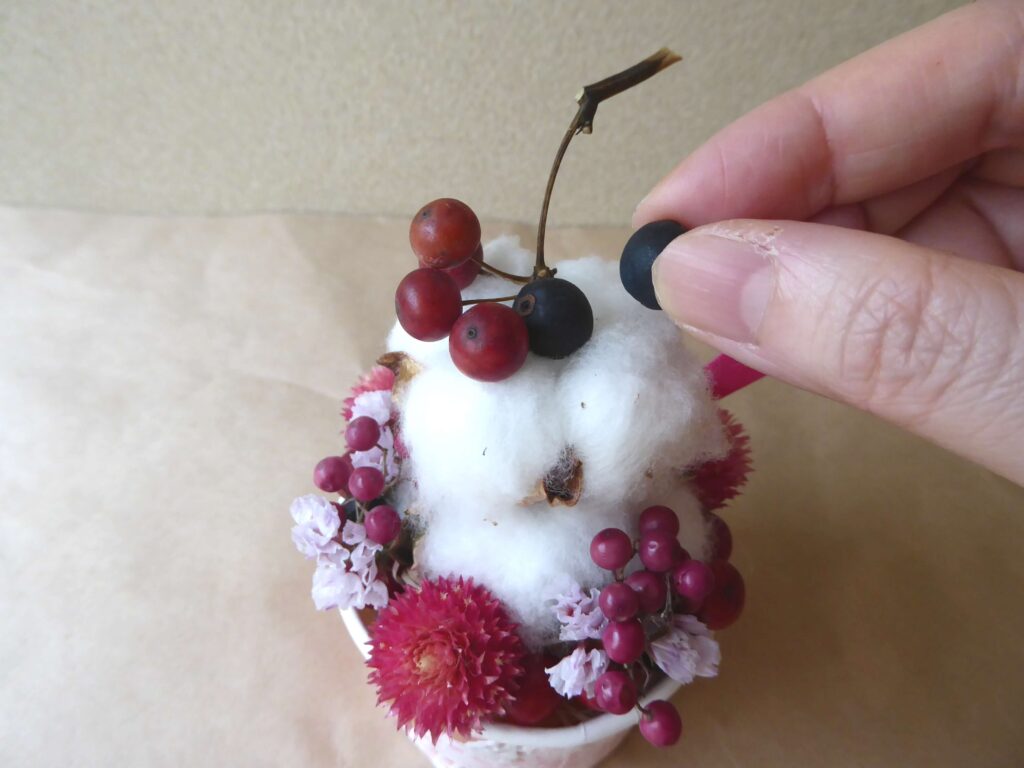 小さい綿の実の上にサンキライとシャリンバイを飾る写真