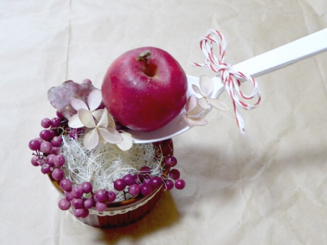 姫リンゴがのったスプーンに紅葉ミナヅキを飾った写真